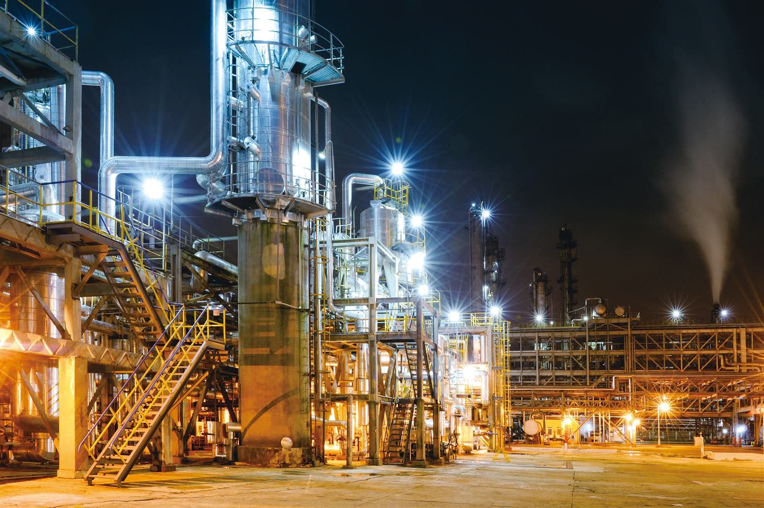 Industrial process plant with pipework and access platforms at night